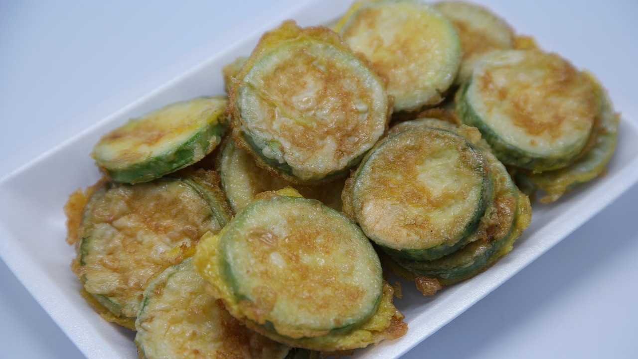 Frittelle di zucchine croccanti servite su un piatto bianco con salsa di accompagnamento.