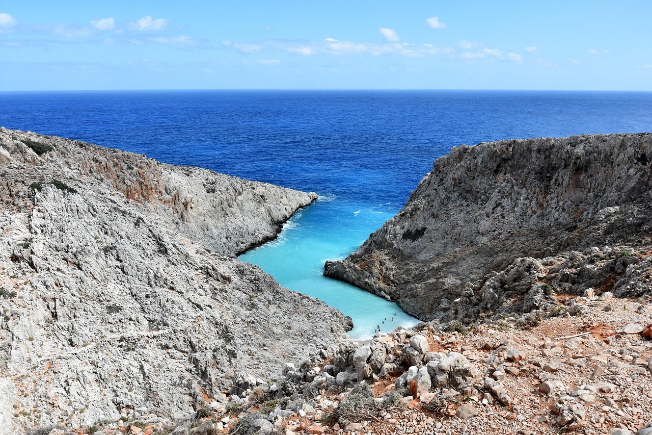 Spiaggia nascosta a Creta, con acque turchesi e sabbia dorata circondata da scogli e vegetazione lussureggiante.
