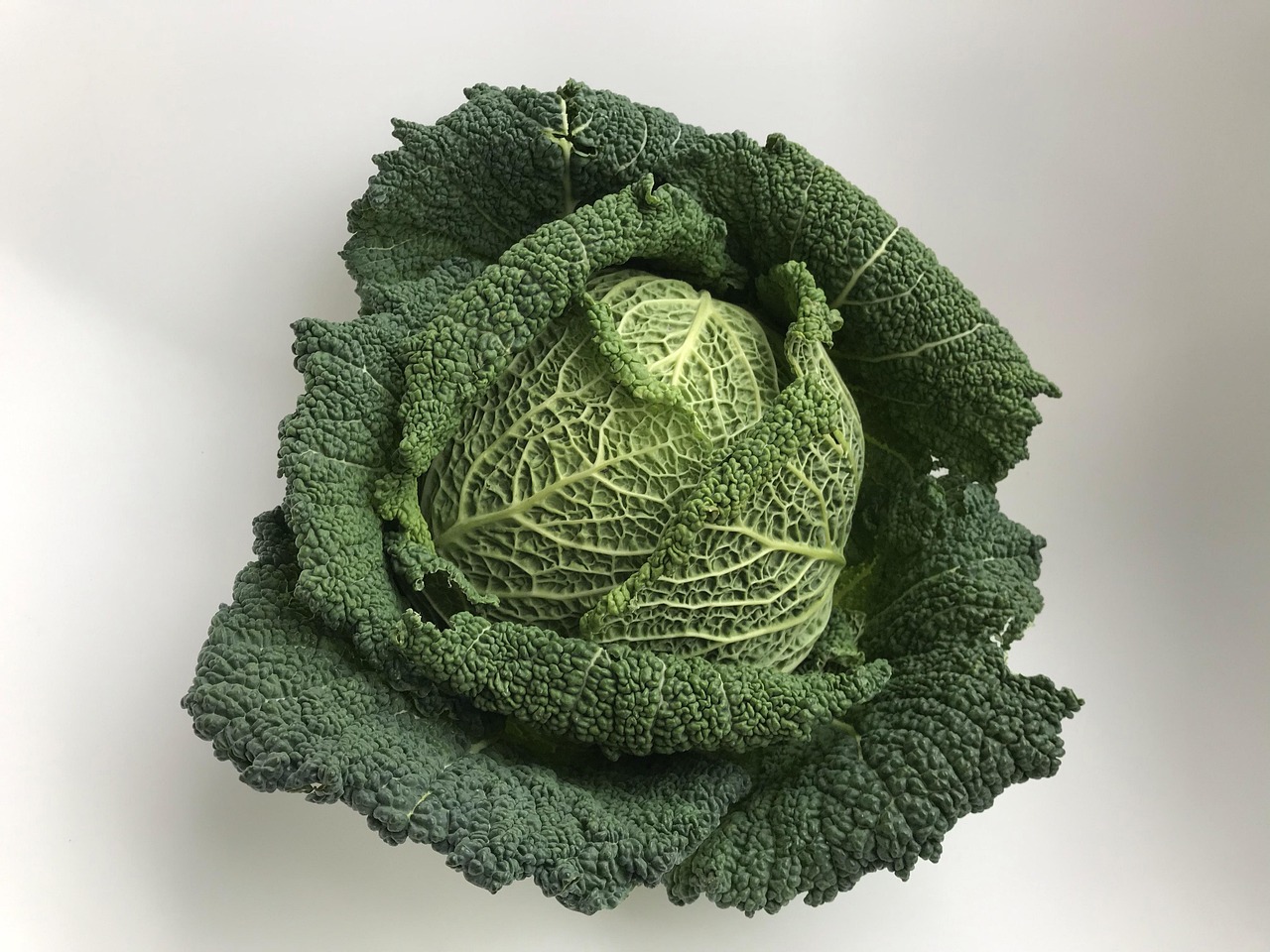 Cavolo nero fresco su un tagliere con utensili da cucina sullo sfondo.