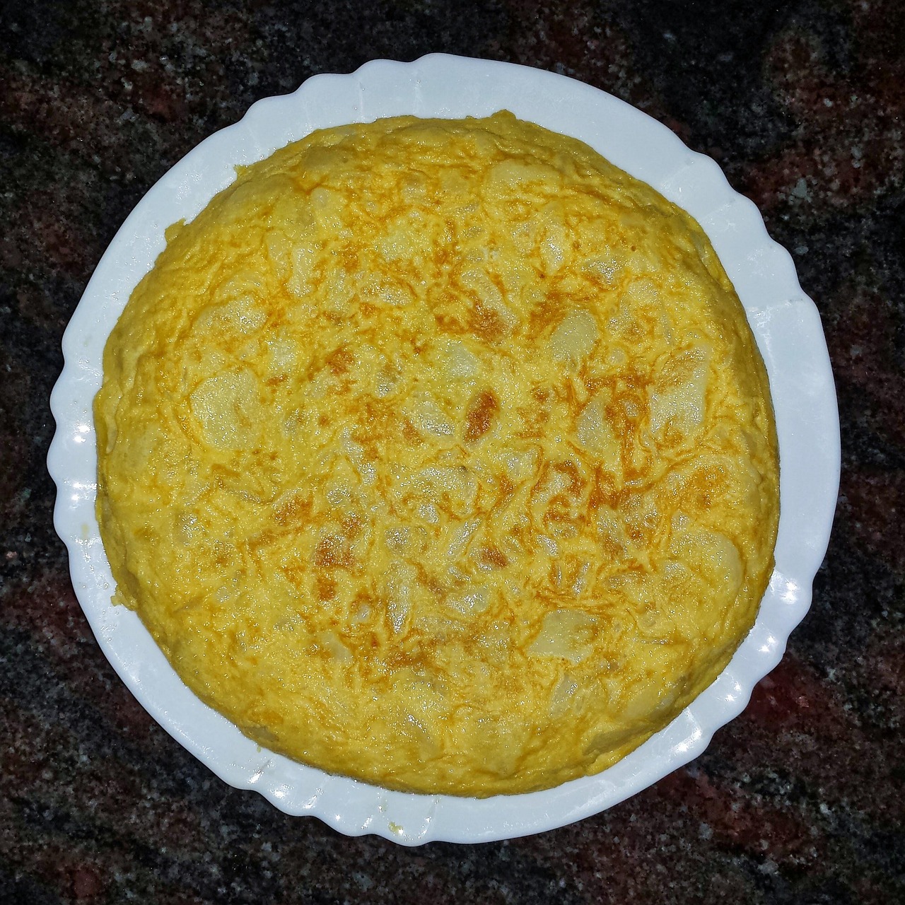 Frittata alta e soffice appena sfornata, servita su un piatto colorato.
