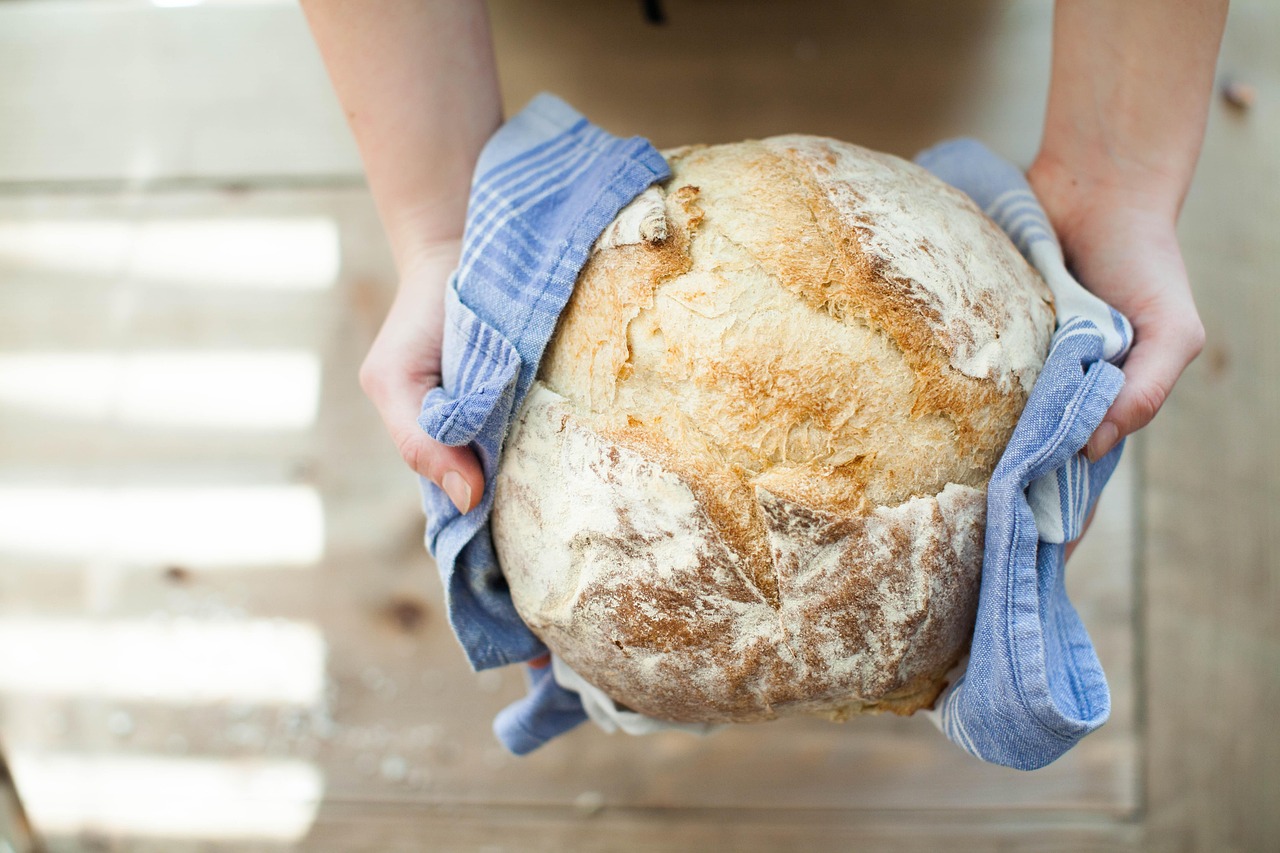 Pane fresco su un tavolo, circondato da ingredienti per conservarlo più a lungo.