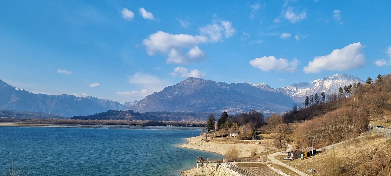 Lago nascosto in Friuli, circondato da montagne e vegetazione lussureggiante.