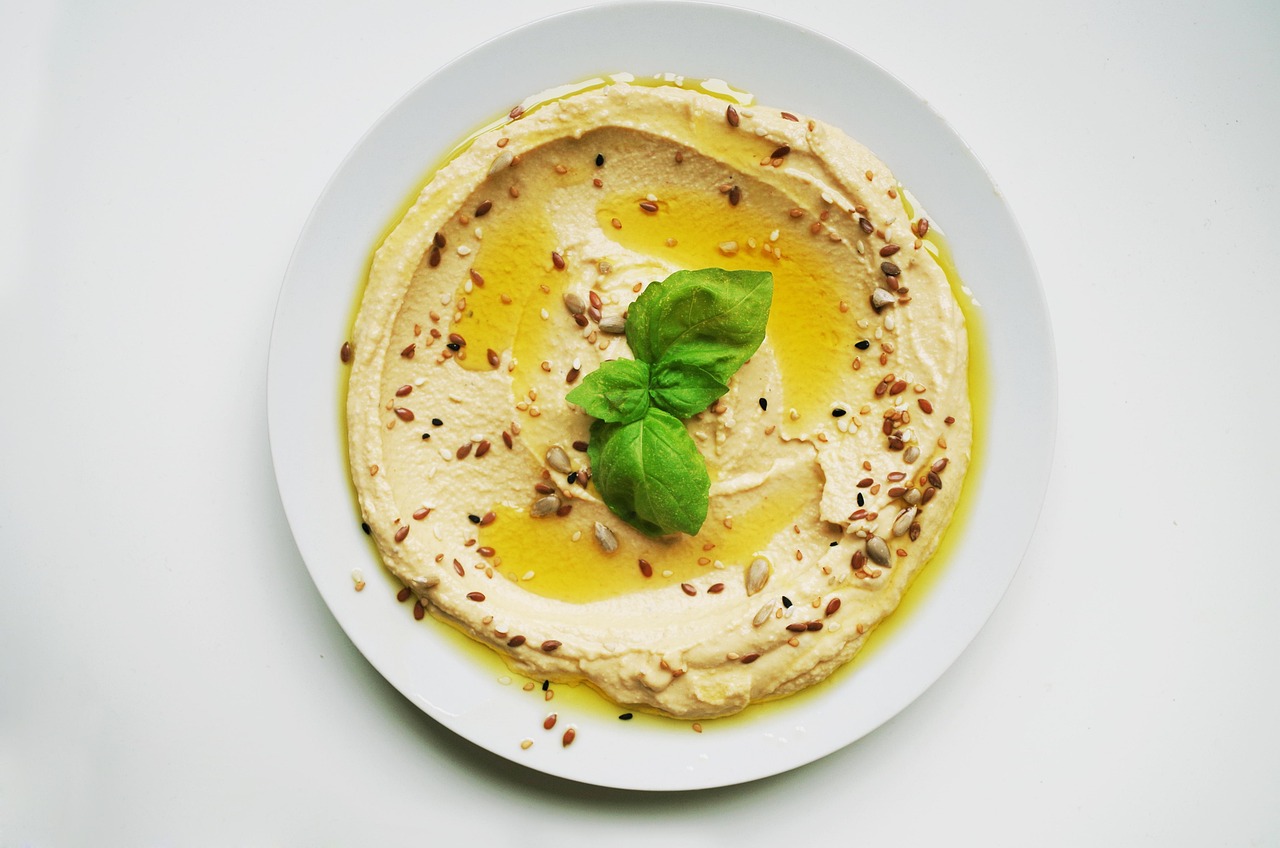 Ciotola di hummus decorata con olio d'oliva e spezie, pronta per essere servita.