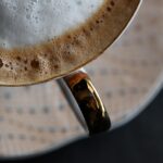 Uomo che prepara schiuma di latte per cappuccino in una ciotola.