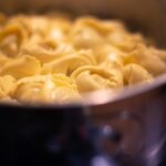 Tortelloni burro e salvia serviti su piatto bianco, decorati con foglie di salvia fresca.