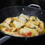 Baccalà alla vicentina cucinato, servito su un piatto con contorni tipici.