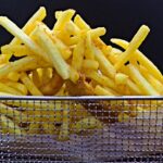 Patatine fritte dorate e croccanti, illustrate con il metodo della doppia frittura a due temperature.
