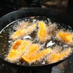 Fetta di mela immersa in olio caldo per friggere senza odori.