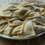 Ravioli fatti in casa con ripieno cremoso su un tavolo di legno.