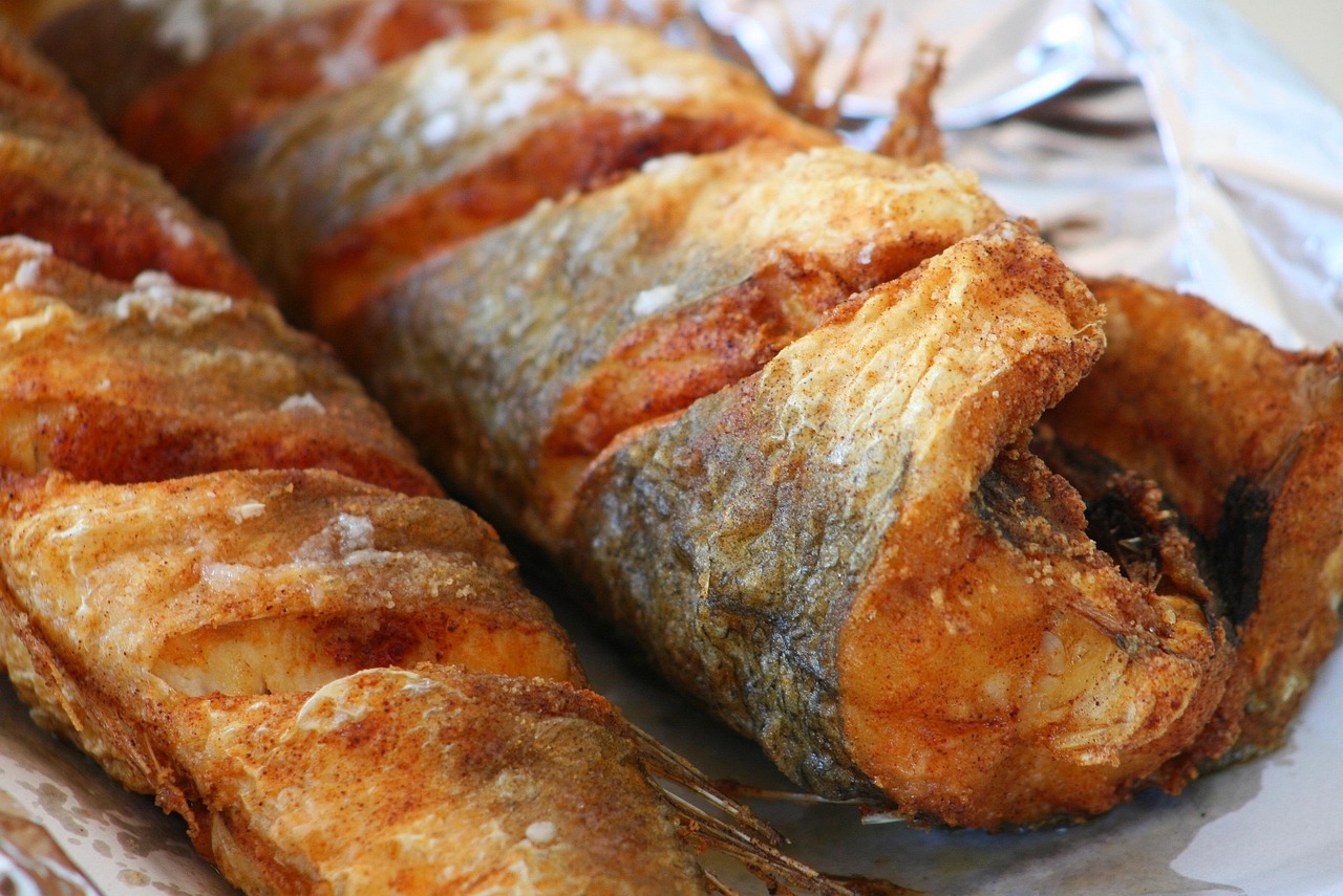 Frittura di pesce dorata e croccante su un piatto, con limone e prezzemolo decorativi.