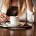 Caffè servito dopo un pranzo, con tazza e piattino su tavolo apparecchiato.