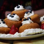 Babà al rum morbido, dorato e decorato con crema, simbolo della tradizione napoletana.