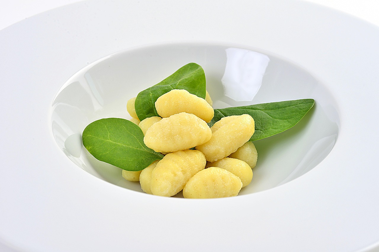 Gnocchi di spinaci e ricotta freschi pronti per essere serviti, conditi e decorati in un piatto.