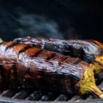 Melanzane grigliate in una ciotola con marinata aromatica e spezie, pronte per essere servite.