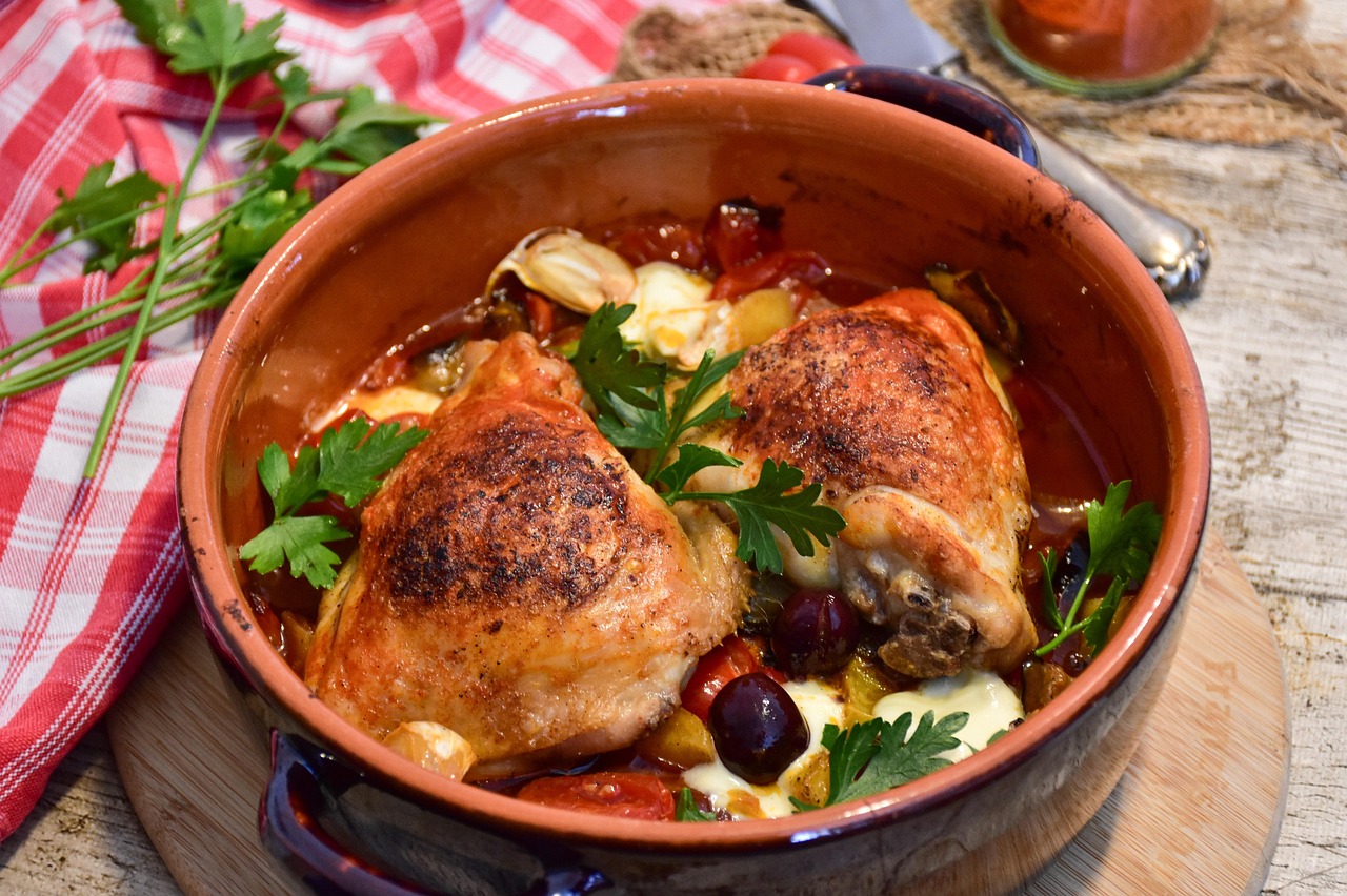 Pollo alla cacciatora con pomodori, olive e rosmarino in un piatto rustico.