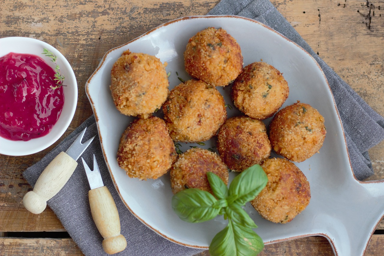 Deliziosi arancini siciliani dorati, pronti per essere gustati, con ripieno di riso e ragù.