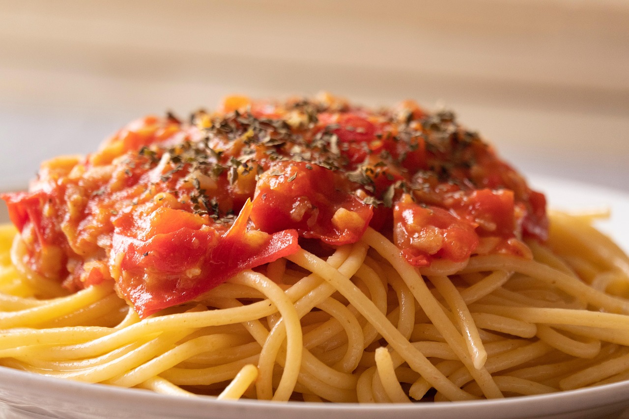 Spaghetti al pomodoro con salsa fumante, piatto decorato con basilico fresco.